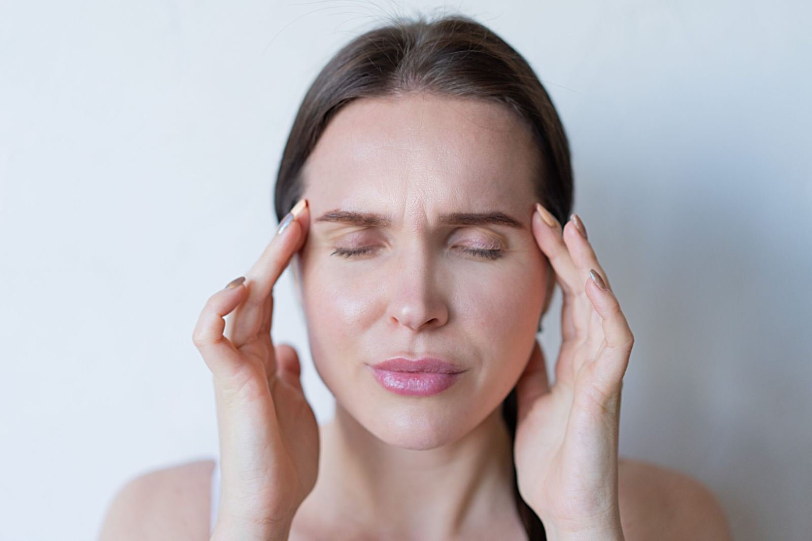 Woman holding temples experiencing migraine headache pain - Ayurvedic migraine treatment in Jaipur